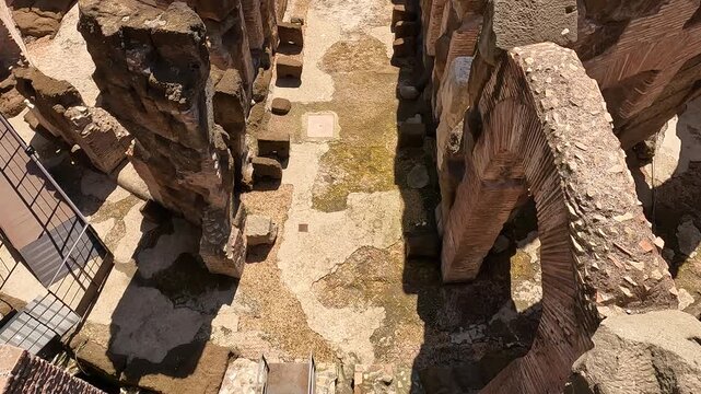 Stunning interior view of the Colosseum hypogeum in Rome, Italy, revealing the ancient underground tunnels and chambers beneath the arena floor with tourists visiting.