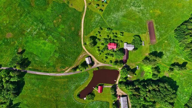 A slow, cinematic zoom-in on a peaceful farmstead featuring a red roof house and a garden pond.