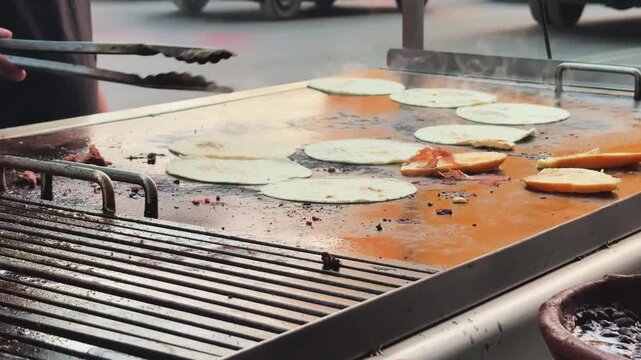 Authentic Mexican street food being prepared on a griddle in Mexico City. Close-up of tortillas and meat cooking on a flat top grill at a traditional food stall in the CDMX historic center