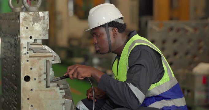 A technician performs precision grinding and close inspection on a metal component in a manufacturing facility, showing finishing work, process control, and industrial supervision.
