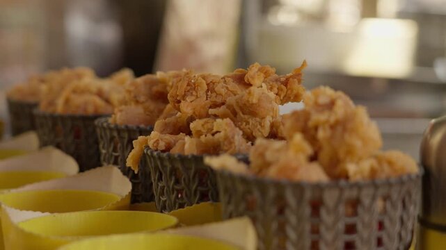 Crispy fried snacks served in small paper cups at food stall, showing ready to eat street food, quick serving style, local snack culture, everyday market food scene
