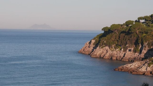 Cliff in the coastline of Lazio region at sunrise with the promontory od Circeo in the background, Italy