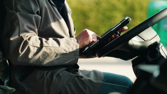 Worker inspecting a truck and taking notes on a tablet outdoors with greenery in the background.
