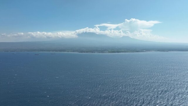 Cloud-capped Volcano Mount Ijen Across Bali Strait In Indonesia. wide aerial shot