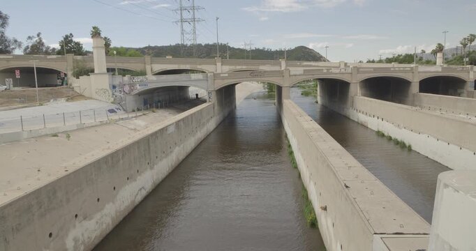 Cinematic daytime 4K 10-bit footage capturing an aqueduct bridge structure spanning the Los Angeles River corridor.