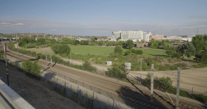 Cinematic daytime 4K 10-bit footage captured from the historic North Broadway Bridge overlooking Los Angeles State Historic Park below. The shot showcases the park&rsquo;s expansive green lawns.