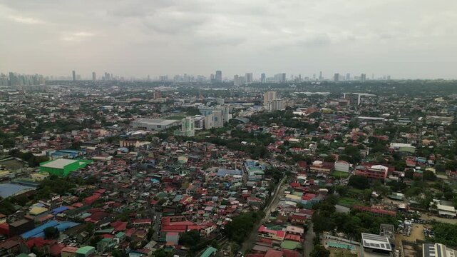 Aerial flyover shot of Antipolo, Philippines showcasing dense residential areas with distant skyscrapers under a cloudy sky.
