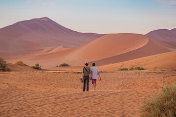 Fototapeta premium Mother and boy walking in the dunes near Sossuvlei, Namibia