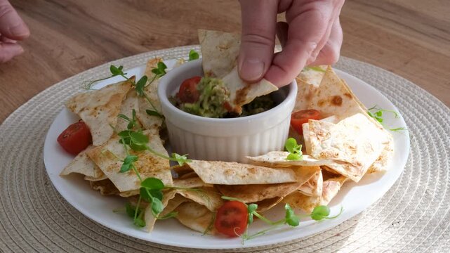 Hand dipping crispy chips into fresh guacamole video