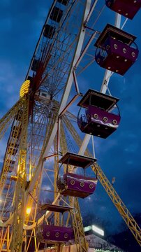 Illuminated Ferris Wheel Spinning at Twilight under Dramatic Sky