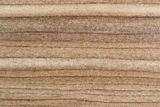 Close-up background of horizontal wood grain texture with light brown and beige tones. High-pressure laminate (HPL) surface with a linear pattern, suitable for interior design.