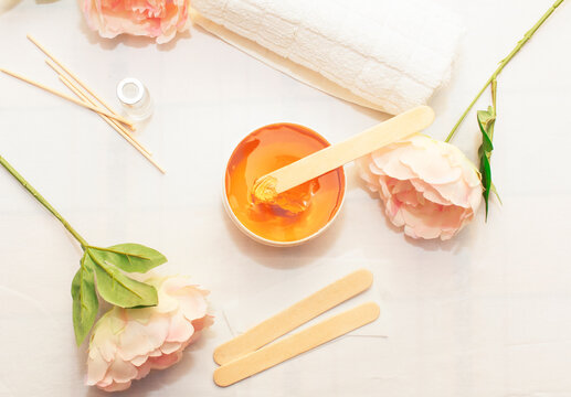 Liquid yellow paste for shugaring on a wooden stick, close-up.