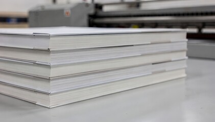 Fototapeta premium Medium shot capturing textbook paperbacks collated and stacked neatly sharp focus on edge alignment while automated equipment in the background remains softly out of focus.