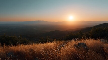 Naklejka premium Golden hour sunlight illuminates vast fields of tall grass set against a breathtaking backdrop of layered mountains at sunset