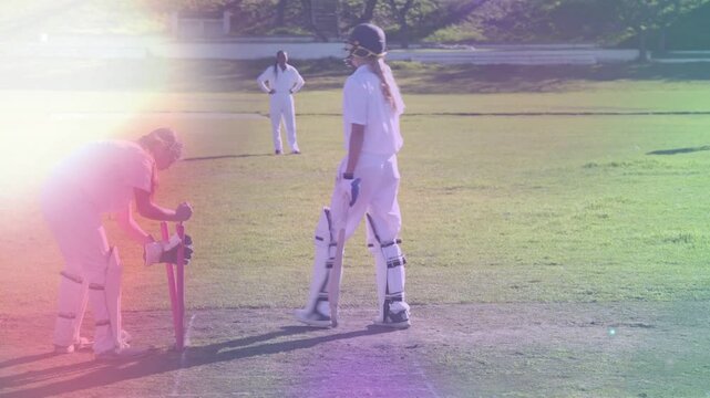 Teammate fixing pink stumps making batter pacing crease, lifting bat and resetting guard in cricket