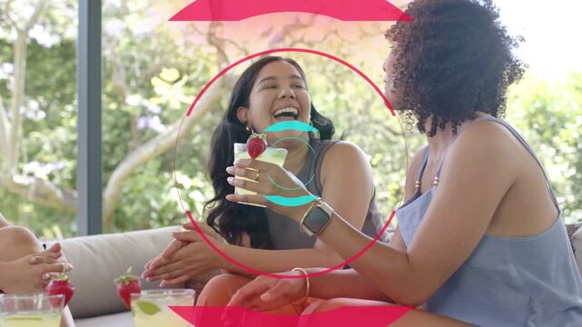 Duo sitting on sofa, circles fading over them, right woman raising drink, center holding lifestyle