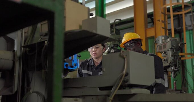 Technicians performs precision grinding and close inspection on a metal component in a manufacturing facility, showing finishing work, process control, and industrial supervision.
