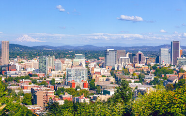 Obraz premium Portland's dense urban skyline nestled among lush greenery, with the snow-capped peak of Mount Hood looming majestically on the clear blue horizon.