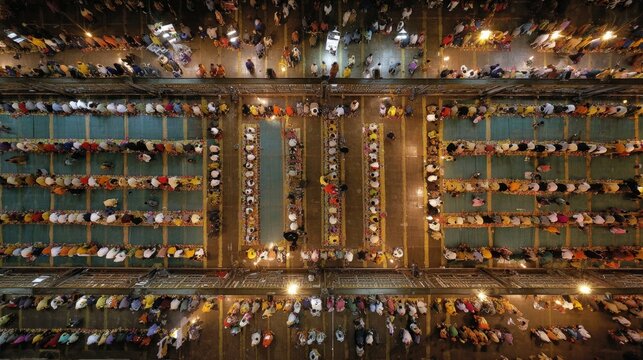 Aerial view of a langar hall (community kitchen) during Vaisakhi, long rows of people sitting on the floor eating together,