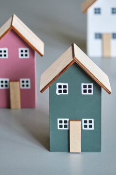 Three miniature houses in red, green and white on a gray background. Real estate industry, affordable housing, mortgage, eco-friendly, energy neutral and building insulation concept.	