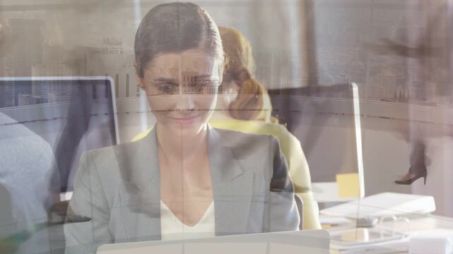 Seated woman working at laptop, typing in office, walkers creating ghosted figures across desk