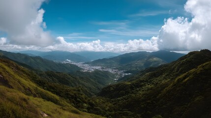 Obraz premium Breathtaking panoramic view of lush rolling mountains and valleys beneath a dramatic expanse of blue and white sky