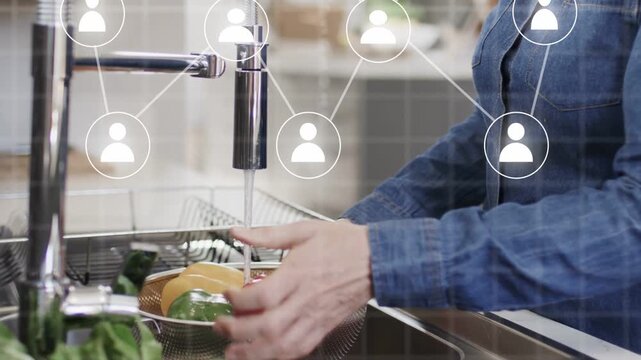 Vertical video: Positioning colander starting tap, senior in denim rinsing peppers for meal, nodes