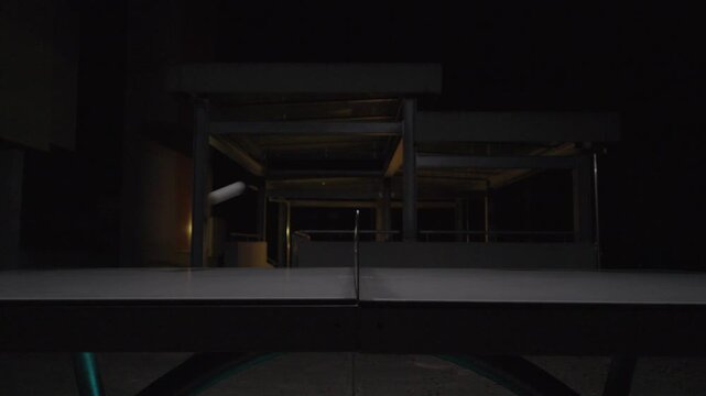 Competitive table tennis match at a outdoor table at night