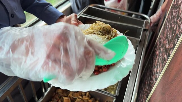 Onboard train meal being plated beside a carriage window on the Hanoi to Hoi An route, showing rice, noodles, braised pork, peanuts, and casual rail catering in Vietnam.