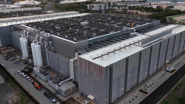 Aerial oblique view of hyperscale data center in Ashburn, Virginia with dense rooftop HVAC cooling systems, industrial chillers and power infrastructure in Data Center Alley tech corridor.
