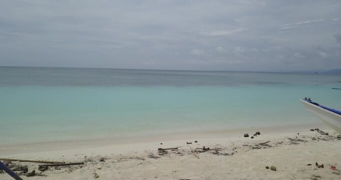 Low altitude drone shot moving slowly forward from sandy beach into clear calm tropical sea in Carabao Island near Boracay Philippines, showing peaceful ocean and shoreline