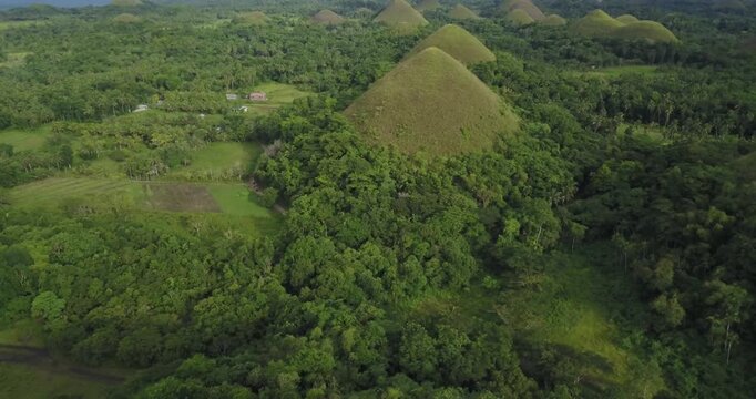 Cinematic drone shot moving forward and ascending from viewpoint revealing the famous Chocolate Hills landscape in Bohol Philippines, lush green tropical scenery and rolling hills