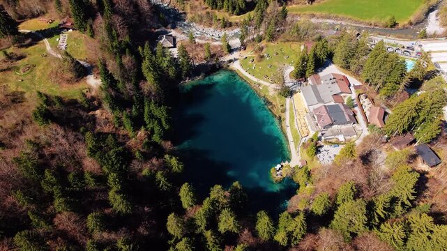 Aerial: Blausee with blue color in Bernese Oberland during the day in Kandergrund, canton of Bern, Switzerland, orbit drone shot