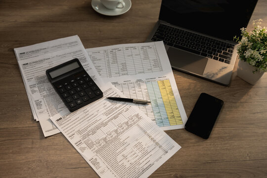 Organized tax filing workspace featuring calculator, laptop, mobile phone, and documents used for accounting preparation, budgeting, expense tracking, financial review, and annual record keeping proce