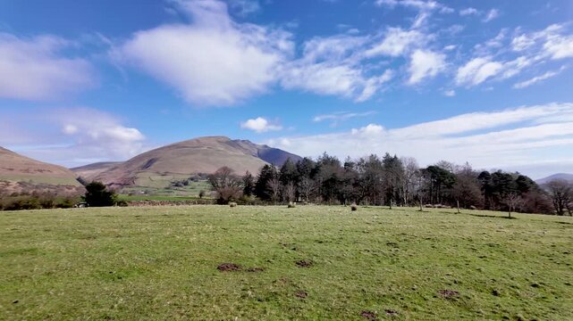 Green fields extending towards distant mountains in Keswick, Lake District National Park