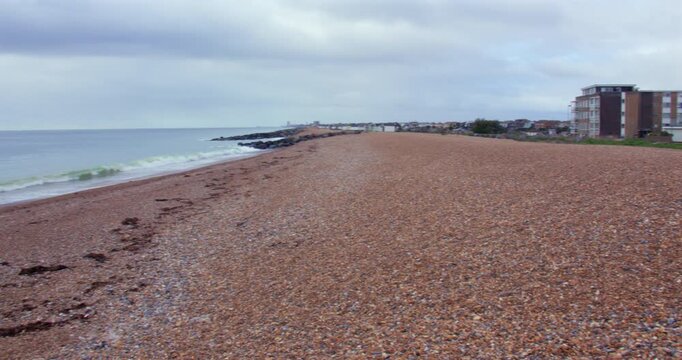 Panning shot looking west up Shoreham beach from houses onto sea
