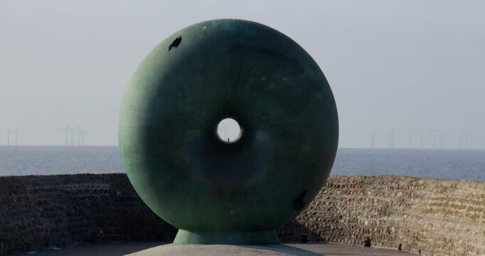 Wide shot of the Afloat Sculpture On Brighton beach next to Brighton pier