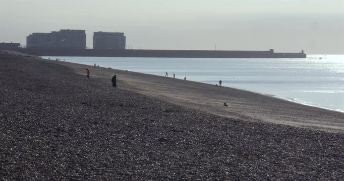 Silhouette shot looking east up Brighton beach on to Brighton Marina