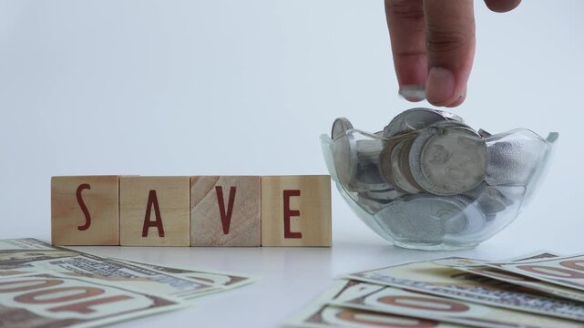 The concept of saving money using wooden blocks with the words SAVE written on them as well as coins and dollars.
