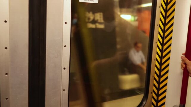 Commuters exiting train through automatic doors, passengers on platform.