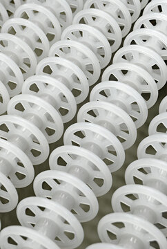 White plastic rollers of industrial conveyor, production, sorting, or transportation line
