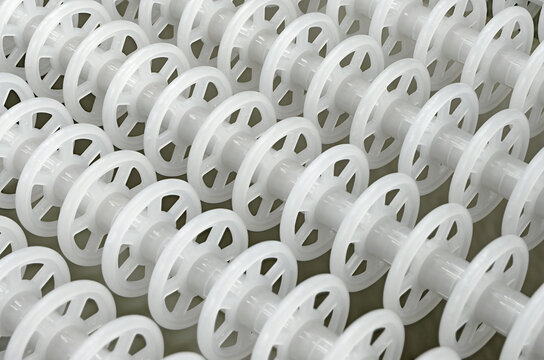White plastic rollers of industrial conveyor, production, sorting, or transportation line