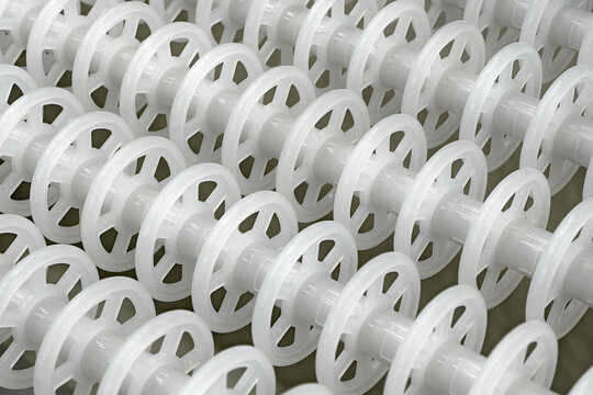 White plastic rollers of industrial conveyor, production, sorting, or transportation line