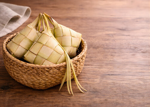 Traditional Thai Sticky Rice Parcels in Woven Coconut Leaves on Rattan Basket, Rustic Wooden Table