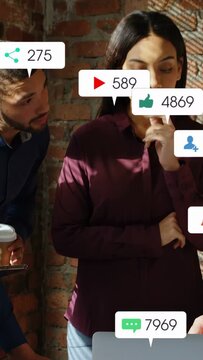 Vertical video: Woman maroon blouse monitoring campaign stats while teammate typing, bubbles rising