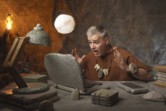 Stressed prehistoric office worker having computer problems
