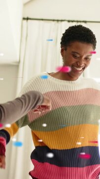 Vertical video: Two women stepping bumping dancing, arm entering frame sparking confetti for ads