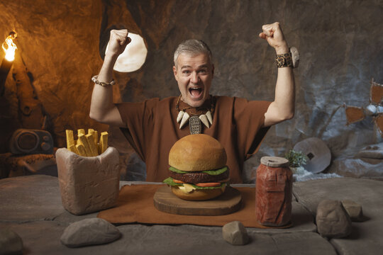 Cheerful caveman enjoying his fast food meal in the cavern