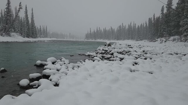 Fly angler walking through fresh untracked snow to a glacial river during snowfall, pausing at the water&rsquo;s edge, conveying solitude, winter wilderness, and exploration.