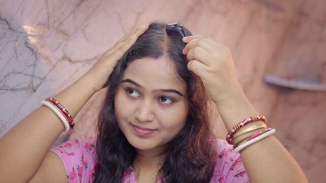 Indian woman performing microneedling with a dermaroller on scalp bald patches in modern bathroom, microneedling treatment for hair loss.
